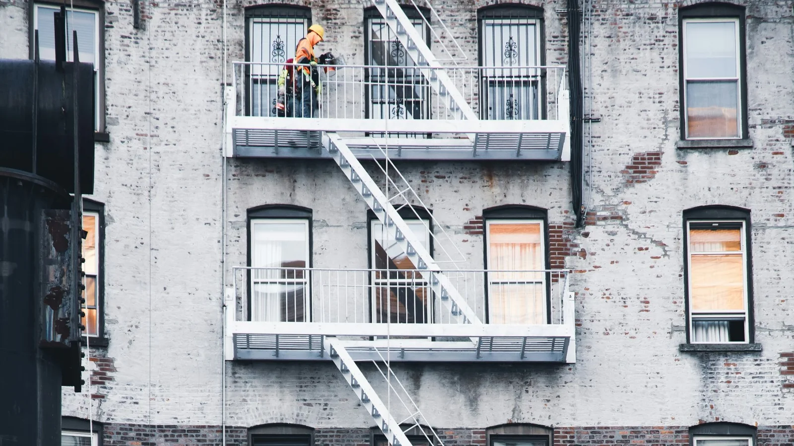 Worker repairing the exterior of a brick multi-unit condominium building, the kind of common element maintenance Illinois condo boards owe owners.