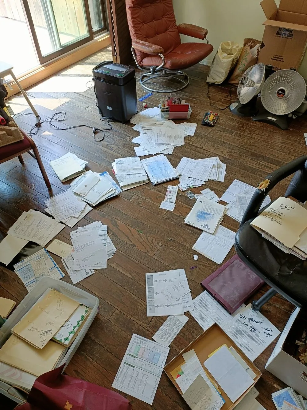Association and personal documents spread across a hardwood floor during an estate cleanout.