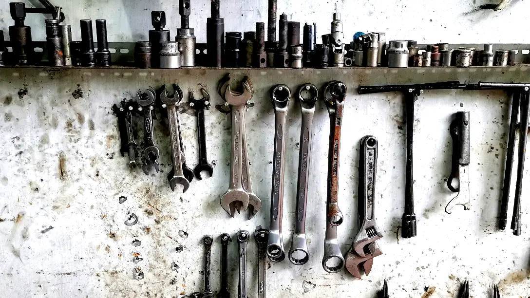 A workshop wall hung with wrenches and sockets of many different sizes.