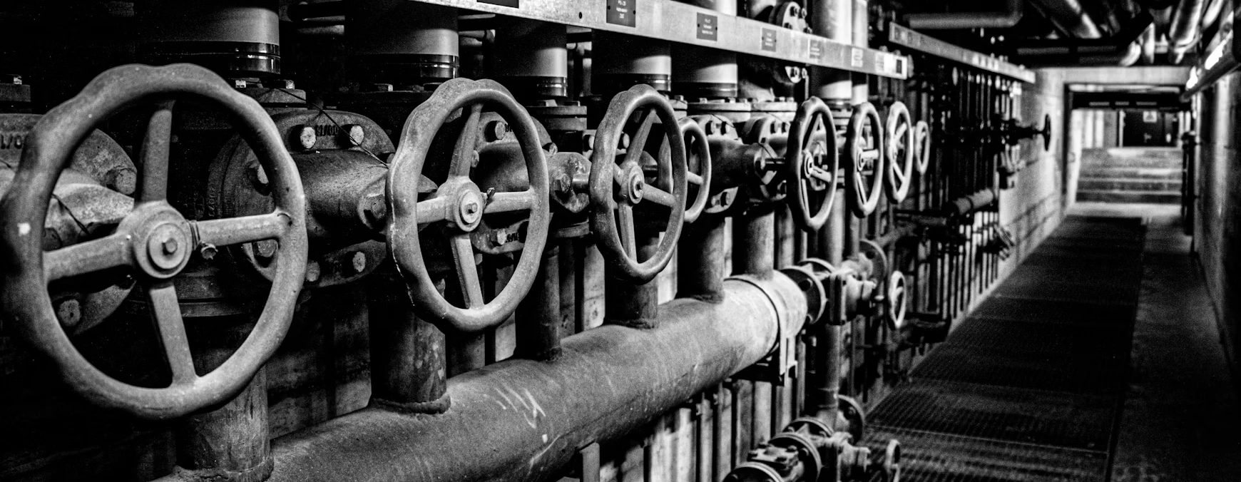 Row of industrial water shut-off valves along a pipe in a building utility corridor